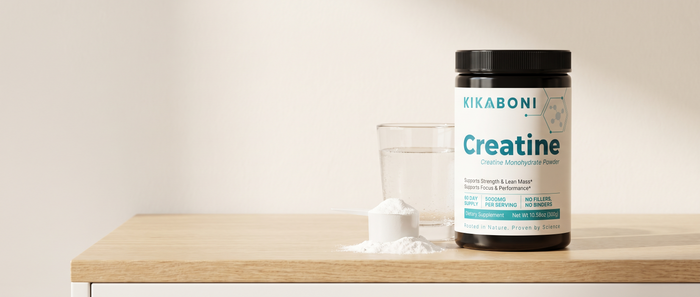 Kikaboni Creatine Monohydrate Powder tub with a scoop of powder and a glass of water